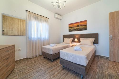 a hotel room with two beds and a dresser at Asfendamos Villas in Zonianá