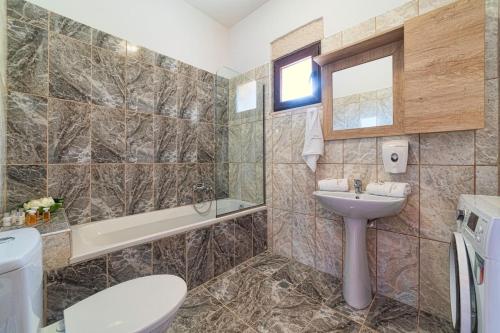 a bathroom with a sink and a toilet and a tub at Asfendamos Villas in Zonianá