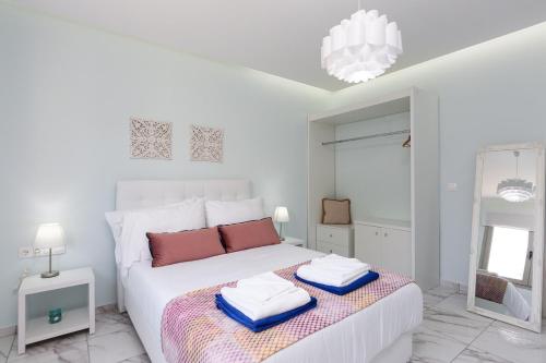 a white bedroom with a bed with towels on it at Villa Vera - With Private Pool & Jacuzzi in Pangalochori