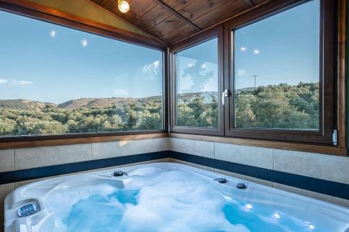 a large bath tub in a room with windows at Villa Staras - With Private Heated Pool & Jacuzzi in Gerani