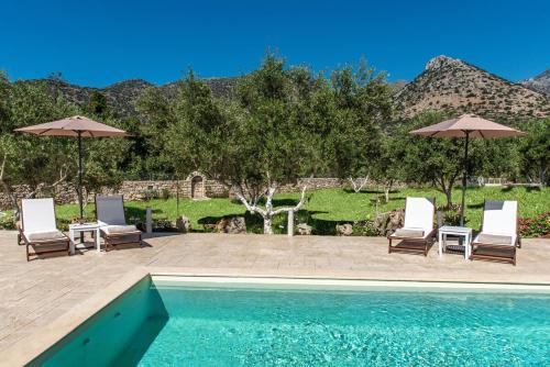 a swimming pool with two chairs and umbrellas at Villa Avra - With Private Pool in Melidhónion