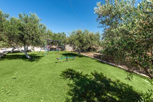 a large yard with a playground in the grass at Villa Avra - With Private Pool in Melidhónion