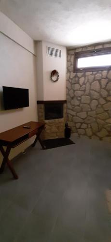 a living room with a stone fireplace and a table at 4 Epohes in Elati Trikalon