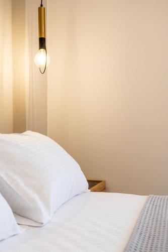 a bed with white sheets and a light on the wall at Villa Karouzo - With Private Pool in Agios Konstantinos