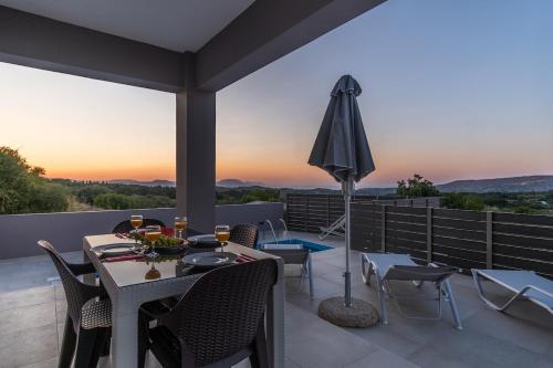 a patio with a table and chairs and an umbrella at Villa Karouzo - With Private Pool in Agios Konstantinos