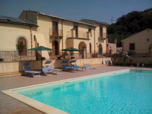 einen Pool vor einem Haus mit Stühlen und Sonnenschirmen in der Unterkunft Patitiri in Santa Teresa di Riva
