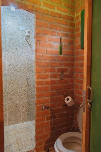 a brick bathroom with a shower and a toilet at Beco das Garrafas in Vale do Capao