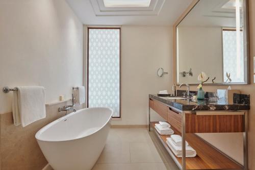 a bathroom with a large white tub and a sink at Fairmont Taghazout Bay in Taghazout