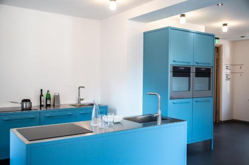 a blue kitchen with a sink and a refrigerator at St.Josefsheim in Schruns