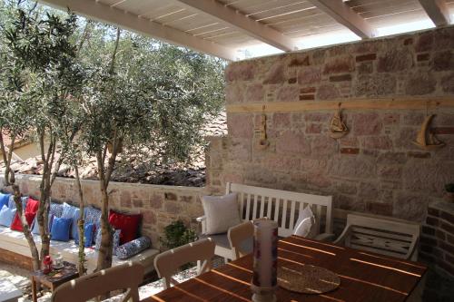 a patio with a table and chairs and a stone wall at Cesmeli Han in Ayvalık