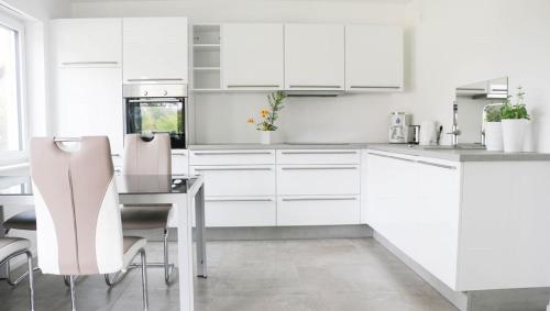a white kitchen with white cabinets and a table and chairs at Ferienwohnung HappyNES in Bad Neustadt an der Saale