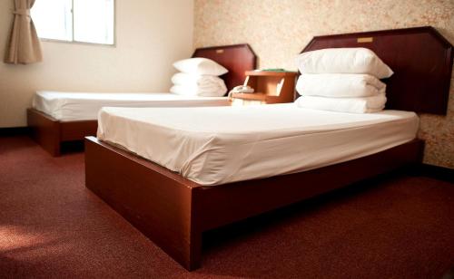 a bedroom with two beds with white sheets and pillows at New May Flower Hotel in Taipei