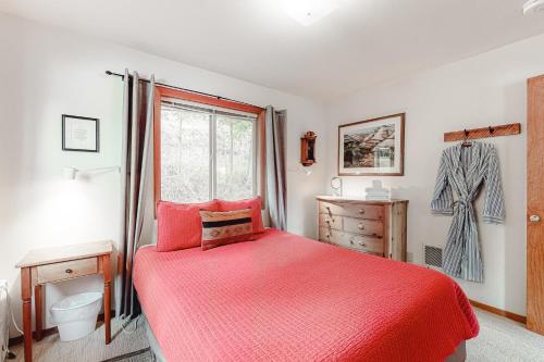 a bedroom with a red bed and a window at Ottertail Cabin in Joseph