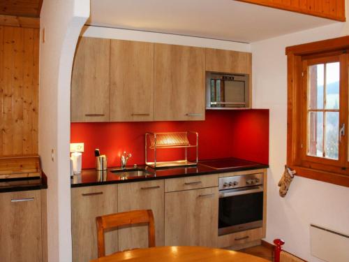 a kitchen with red walls and wooden cabinets at Chalet Chalet 4 pièces 969 by Interhome in Moleson