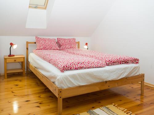 a bed with red and white pillows on it at Malinowy Dworek - Spokojny wypoczynek nad morzem in Ciekocino