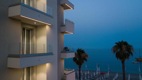 a building with palm trees in front of the ocean at Albatros Beach Hotel in Letojanni
