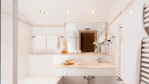 a white bathroom with a sink and a mirror at Superior Hotel Tirolerhof - Zell am See in Zell am See