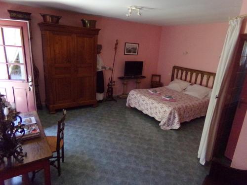 a bedroom with a bed and a table and a television at Chambres et table d'hôtes, maisonnettes individuelles dans propriété privée in Vézinnes