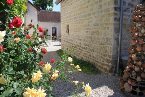 a garden with red and yellow flowers next to a building at Chambres et table d'hôtes Saint Nicolas, maisonnettes individuelles dans propriété privée in Vézinnes
