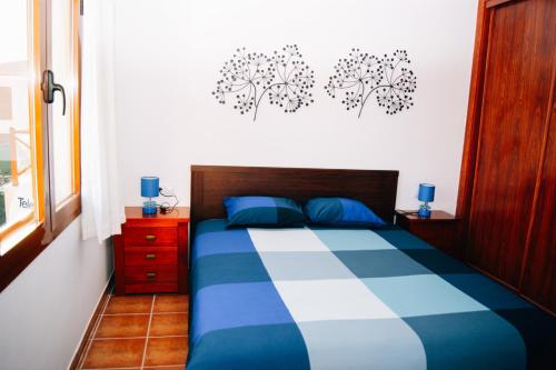 コラレホにあるDuplex con Piscina Corralejo, Wi-fi, TV Satéliteのベッドルーム(青と白のベッド1台、窓付)