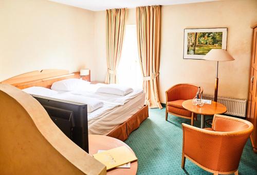 a hotel room with a bed and a table and chairs at Hotel Landhaus an de Dün in Sankt Peter-Ording