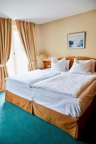 a large white bed in a room with a window at Hotel Landhaus an de Dün in Sankt Peter-Ording