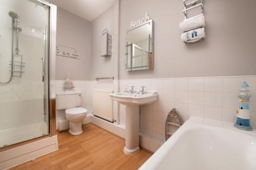 a bathroom with a sink and a toilet and a shower at St Kitts Holiday Apartment in Filey