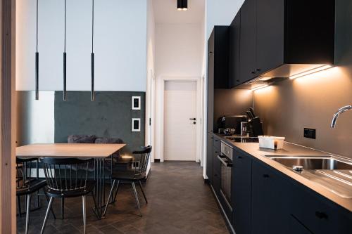 a kitchen with black cabinets and a table with chairs at APART HERZOG - URBAN LUXURY LIFESTYLE direct at Steinbergpiste and Steinbergbahn in Leogang