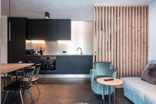 萊奧岡的住宿－Apart Herzog - Design Apartments Leogang direkt an der Steinbergbahn und -piste，厨房以及带沙发和桌子的客厅。