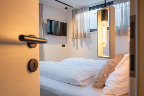 a bedroom with a bed with white sheets and a window at APART HERZOG - URBAN LUXURY LIFESTYLE direct at Steinbergpiste and Steinbergbahn in Leogang