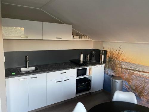 eine Küche mit weißen Schränken und einem Waschbecken in der Unterkunft Sea la vie in Vlissingen