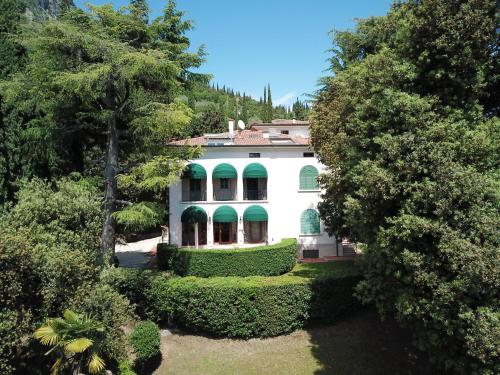 una gran casa blanca con árboles verdes y arbustos en Parco Villa San Vigilio en Garda