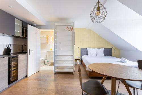 Cet appartement comprend une chambre avec un lit et une table ainsi qu'une cuisine. dans l'établissement Appart Hotel NuitéeJour Le Mans Centre Jaurès, au Mans