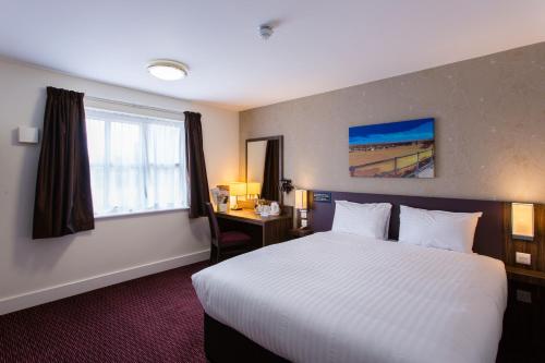 a hotel room with a large bed and a window at Sessile Oak, Llanelli by Marston's Inns in Llanelli