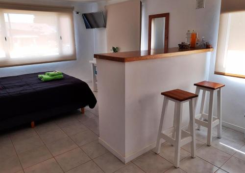 a room with a bar with a bed and two stools at El Garage de los pioneros in El Calafate