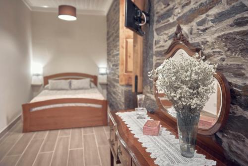 a bedroom with a bed and a vase of flowers on a table at Casa do Largo da Igreja in Vila Nova de Foz Coa