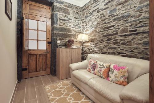 a living room with a couch and a stone wall at Casa do Largo da Igreja in Vila Nova de Foz Coa