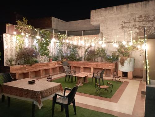 a patio with tables and chairs and lights at The Hideout Agra - Garden Homestay near Taj in Agra