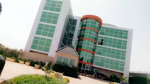 a large green and white building with green windows at Hotel Univers 3 Aeroport Luxe in Niamey