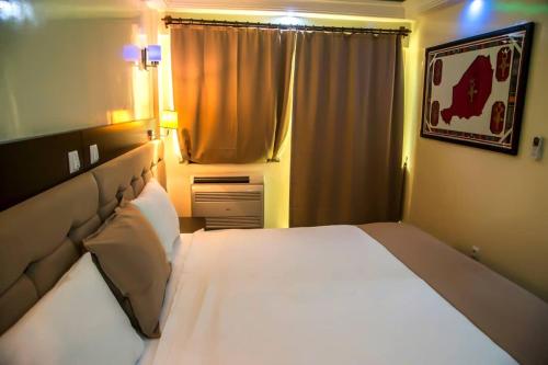 a bedroom with a large white bed and a window at Hotel Univers 3 Aeroport Luxe in Niamey