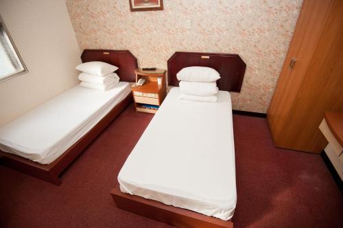 two beds in a small room with white sheets and pillows at New May Flower Hotel in Taipei