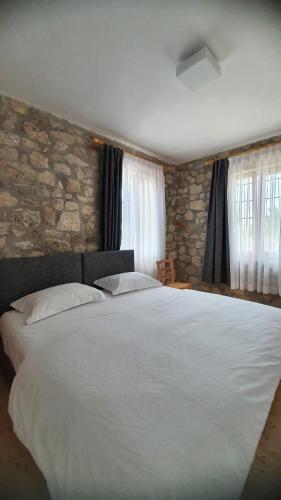 a bedroom with a large white bed with a stone wall at Hani Ilos in Stegopul