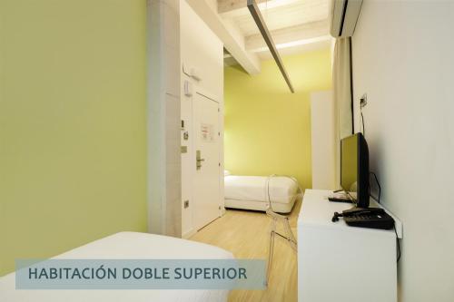 a small room with a bed and a television at Atenas Granada in Granada