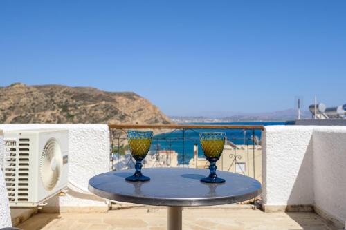 a table with two wine glasses on a balcony at Adonis Hotel in Agia Galini
