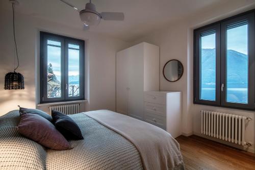 a bedroom with a bed and two windows with mountains at Ortensie & Oleandri al Lago - by MyHomeInComo in Argegno