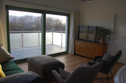 a living room with a large window and a television at Glas Beag in Spean Bridge