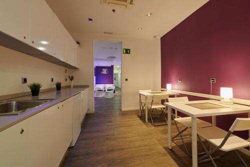 cocina con armarios blancos, mesa y sillas en Hostal Mayerling Centro, en Barcelona