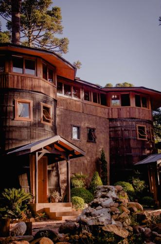 a large wooden house with a stone path in front of it at Refúgio do Caracol Pipas e Chalés in Canela