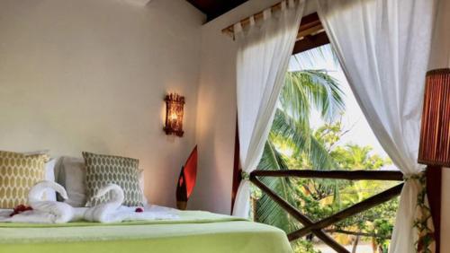 a bedroom with two swans on a bed with a window at Paradise Beach House in Imbassai