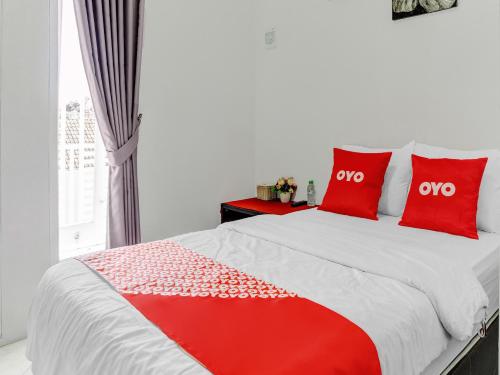 a bedroom with a bed with red pillows and a window at Super OYO 90730 Padekosan in Tulungagung